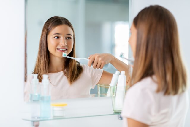 鏡の前で歯磨きをする髪の長い若い女性