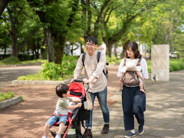 ベビーカーを押すパパと抱っこひもで赤ちゃんを抱っこしているママ