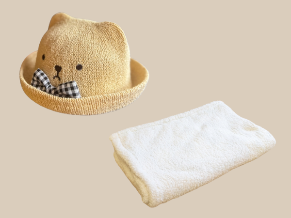 赤ちゃんの熊の帽子とクリーム色のブランケット