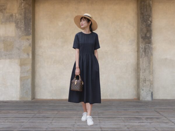 紺色の麻のワンピースを着て麦わら帽子をかぶった女性