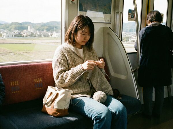 電車内で編み物をする若い女性